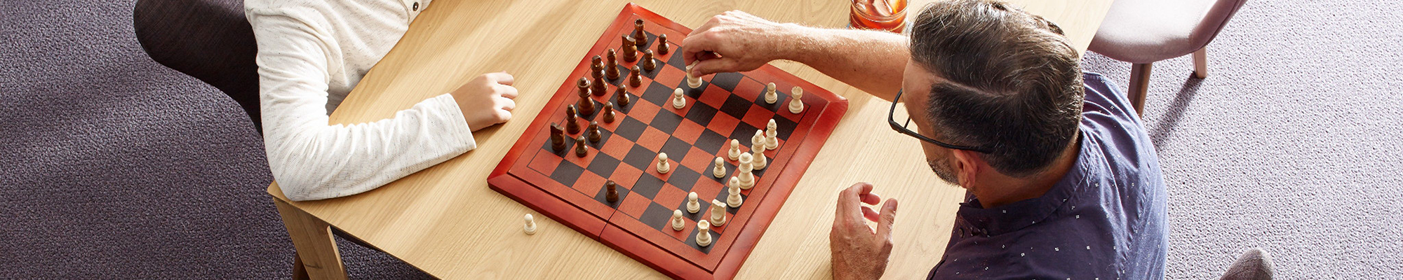 father and son playing chess on table